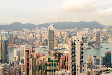 Fototapeta premium Landscape of scenery aerial view on top of buildings in town Hong Kong. City with white cloudy by bright sunlight in evening with hotels and office towers with orange sunlight in evening is background