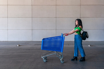 Young woman walking with shopping cart in supermarket parking lot