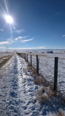 Snow-covered road and fence under a bright sun