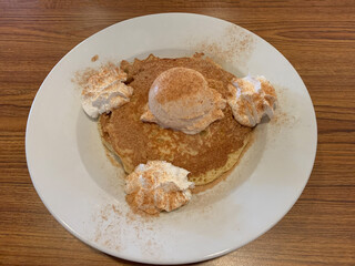 Plate with delicious pancakes sprinkled with cinnamon sugar and topped with ice cream and whipped cream