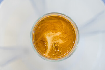 A glass of espresso shot over cold fresh milk create gradient layer called dirty coffee. Top view