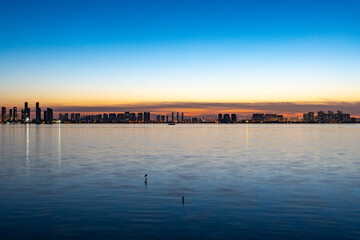 Fototapeta premium China Tangxun Lake Jiangxia Wuhan City skyline reflects on calm waters at dusk.
