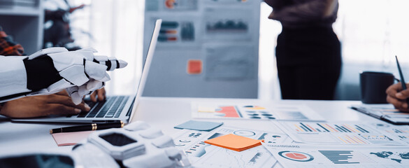 A modern office scene showcasing collaboration between human and robot, focused on data analysis and strategy development with vibrant charts and documents.Noogenesis