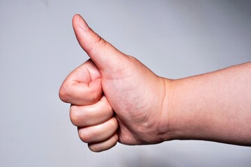Anonymous hand with thumbs up gesture or pose isolated on horizontal ratio gray background.