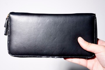 Women hand holding old black wallet isolated on horizontal white background.