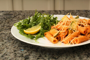 Closeup of prepared rigatoni pasta dish with zucchini and arugula