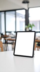 Fototapeta premium Blank tablet screen on a white table in a modern cafe.