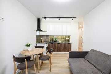 modern, compact studio apartment featuring a kitchen, dining area, and living space with neutral tones and minimal decor