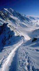 Snow-covered mountain ridge path descends into valley
