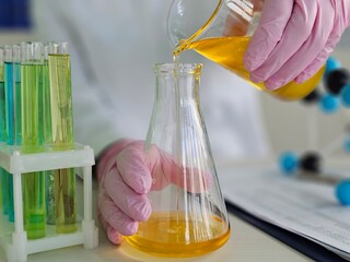 Laboratory technician conducts chemical experiment pouring liquid into flask during research session at science facility