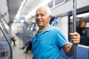 Old man standing in subway car