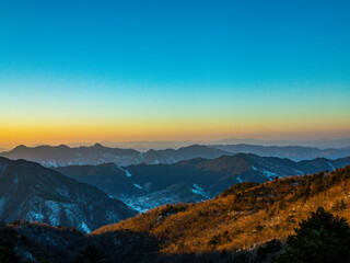 Obraz premium Snowy Mountain Summit at Dusk with Setting Sun Panorama