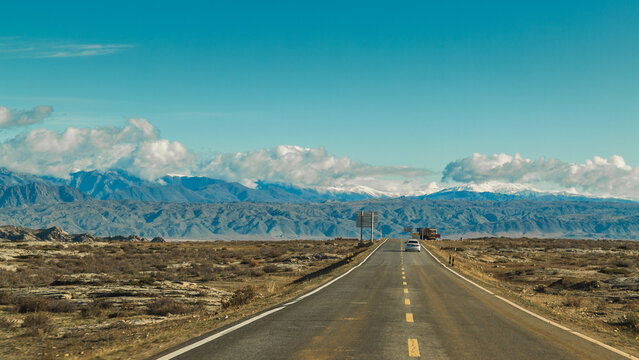 Spectacular Mountain Highway Winding through Snow-Capped Xinjiang Peaks under Dramatic Skies