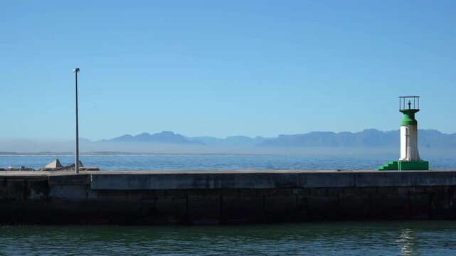 Jetty light and lighthouse protected by dolos with mountain and sea views
