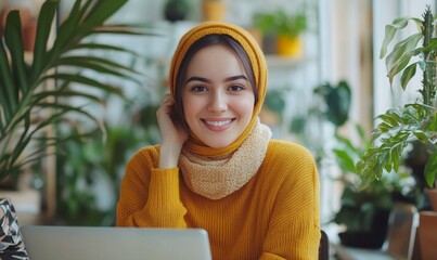 Happy female digital nomad wearing a hijab, smiling while working remotely on a laptop during a virtual video call with colleagues. This image represents an inclusive and diverse, Generative AI