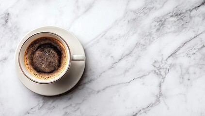 Overhead view of a cup of black coffee on a marble surface