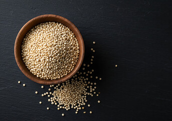 Wooden bowl filled with quinoa sits on a dark slate surface, showcasing healthy eating and natural texture in a minimalist style.