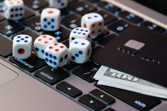 Laptop keyboard with dice, credit card and cash, concept of online gambling, betting and casino games in digital world