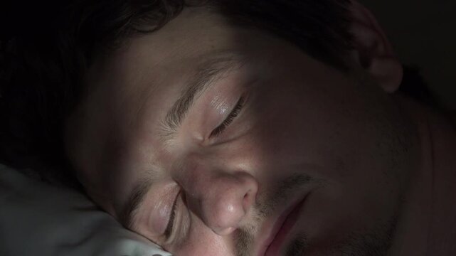 Adult male sleeping wakes up with sunlight across face 4k