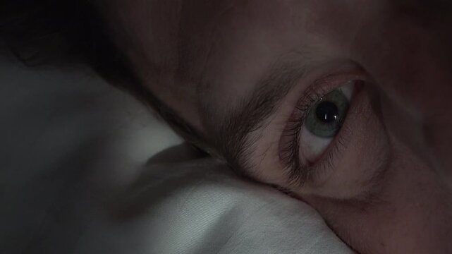 Man looking at camera with eyeball laying on pillow 4k