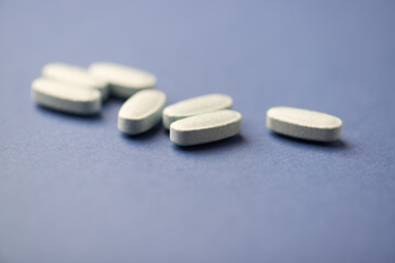 Multivitamin tablets on bright paper background. Close up. Copy space	