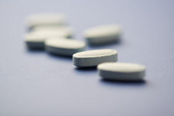Multivitamin tablets on dark paper background. Soft focus. Close up. Copy space	