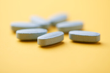 Multivitamin tablets on bright paper background. Close up. Copy space	