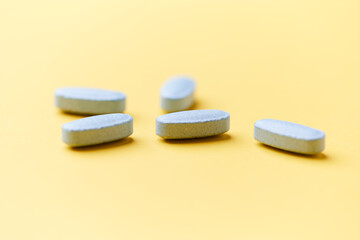 Multivitamin tablets on bright paper background. Close up. Copy space	