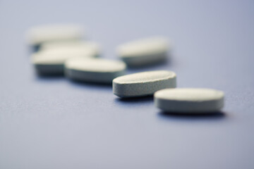Multivitamin tablets on dark paper background. Soft focus. Close up. Copy space	