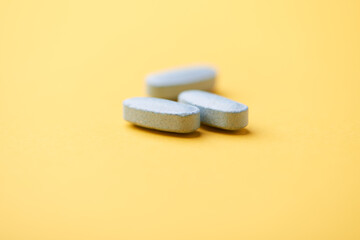 Multivitamin tablets on bright paper background. Close up. Copy space	