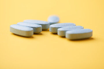 Multivitamin tablets on bright paper background. Close up. Copy space	