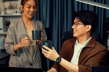 Sales managers discussing while drinking coffee cup together at over late night at home office, concept of modern working place with business report at breaking time with coworker at desk. Infobahn.