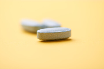 Multivitamin tablets on bright paper background. Close up. Copy space	
