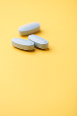Multivitamin tablets on bright paper background. Close up. Copy space	