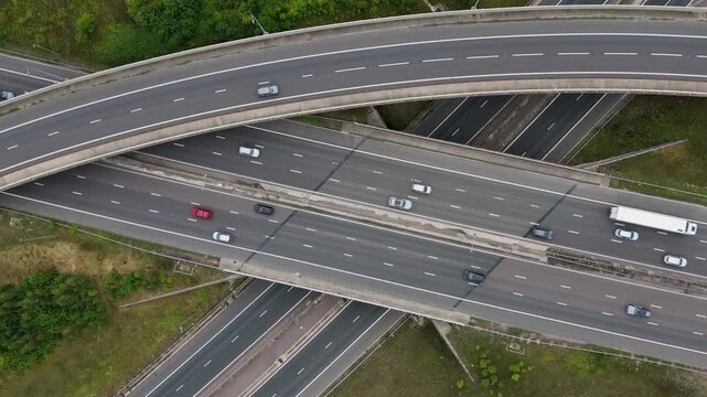 Wide aerial drone view of busy motorway interchange with vehicles navigating flyovers and junctions near Birmingham England UK