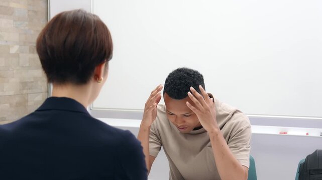 悩む黒人男性と面談する日本人女性スタッフ