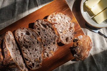 cranberry walnuts sourdough bread sliced placed on wooden cutting board.