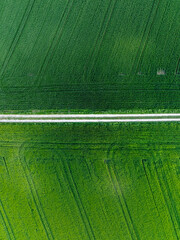 Aerial view of rural road through countryside meadows and farmland in Canton of Fribourg in Switzerland. 