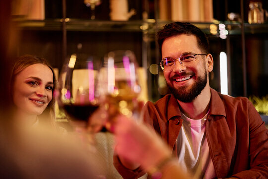 Happy People Toasting Drinks During Social Gathering in a Cozy Night Setting