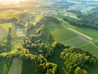 Aerial view of rural landscape in Swiss canton of Fribourg. Hills and forests in evening sunlight in district of Sense.