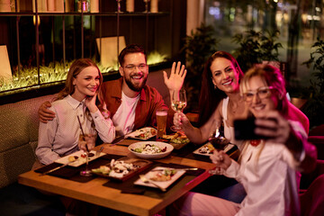 Group of Friends Enjoying Dinner and Taking Selfies at a Restaurant