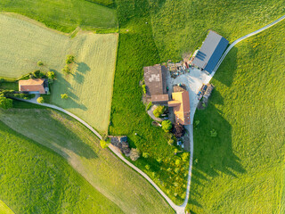 Aerial view of farm house in Switzerland in Canton of Fribourg. Rural fields in evening sunlight.