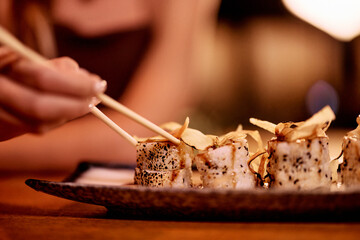 Close-Up of Gourmet Sushi Roll with Chopsticks in a Restaurant Setting