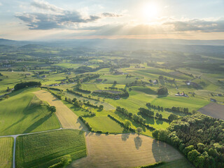 Aerial view of rural landscape in Swiss canton of Fribourg. Hills and forests in evening sunlight in district of Sense.