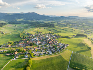 Aerial view of rural landscape in Swiss canton of Fribourg. Hills and forests in evening sunlight in district of Sense.