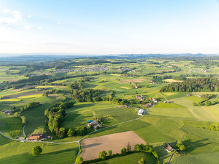 Aerial view of rural landscape in Swiss canton of Fribourg. Hills and forests in evening sunlight in district of Sense.