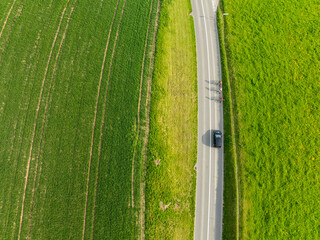 Aerial view of rural road through countryside meadows and farmland in Canton of Fribourg in Switzerland. 