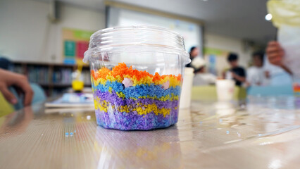 Colorful layered salt art in plastic cups, elementary school craft project