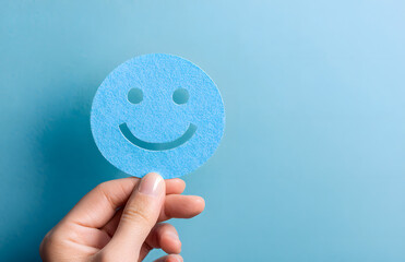 Hand holding blue paper cut happy smile face, positive thinking, mental health assessment , world mental health day concept