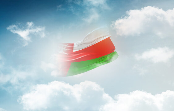 Oman flag waving light background hidden in the sky.